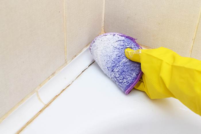 A Woman's Hand In A Yellow Glove Cleans The Tiles In The Bathroom With Detergent.cleaning The House.cleaning Of Dirty Plaque